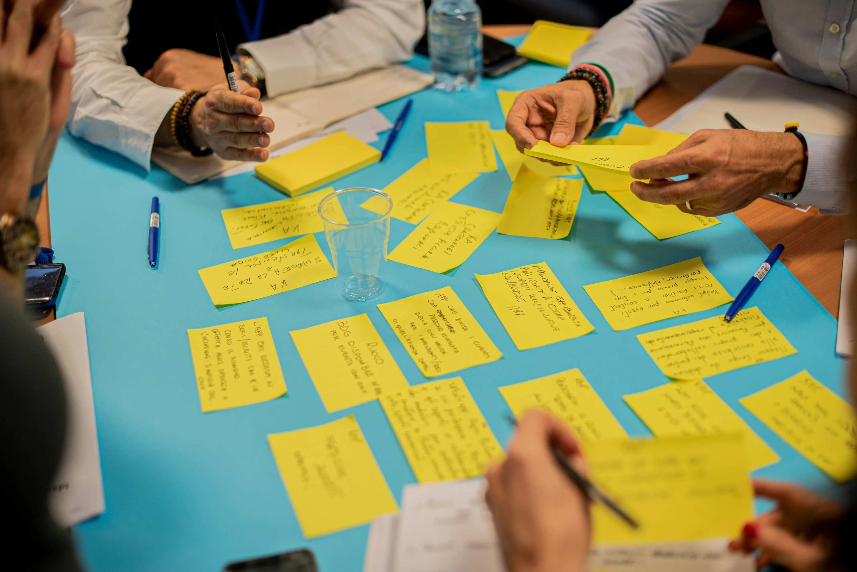 People gathered around a table covered in yellow sticky notes during a workshop or brainstorming session.