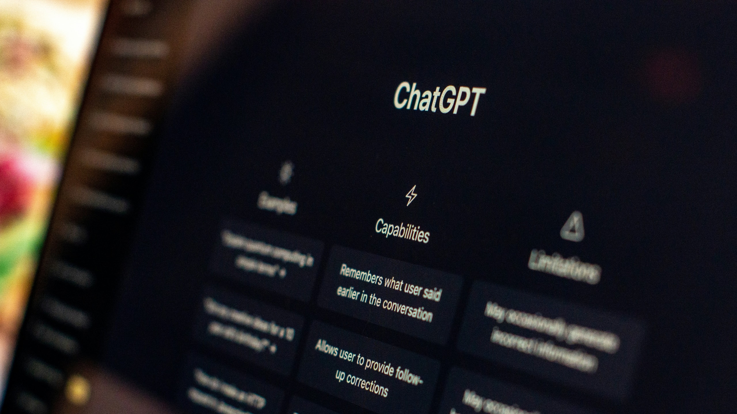 ChatGPT welcome screen on a dark monitor, showing Capabilities and Limitations columns.