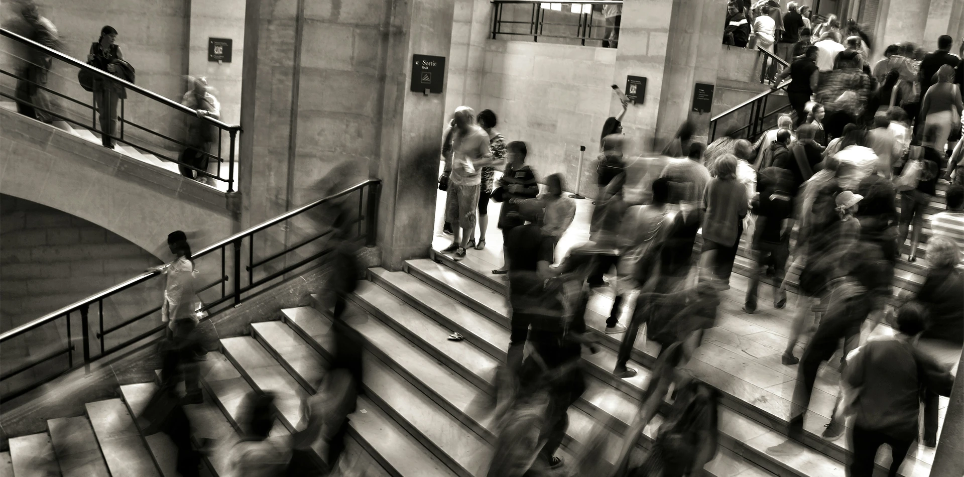 Sepia photo of people walking up and down stairs in an office building.