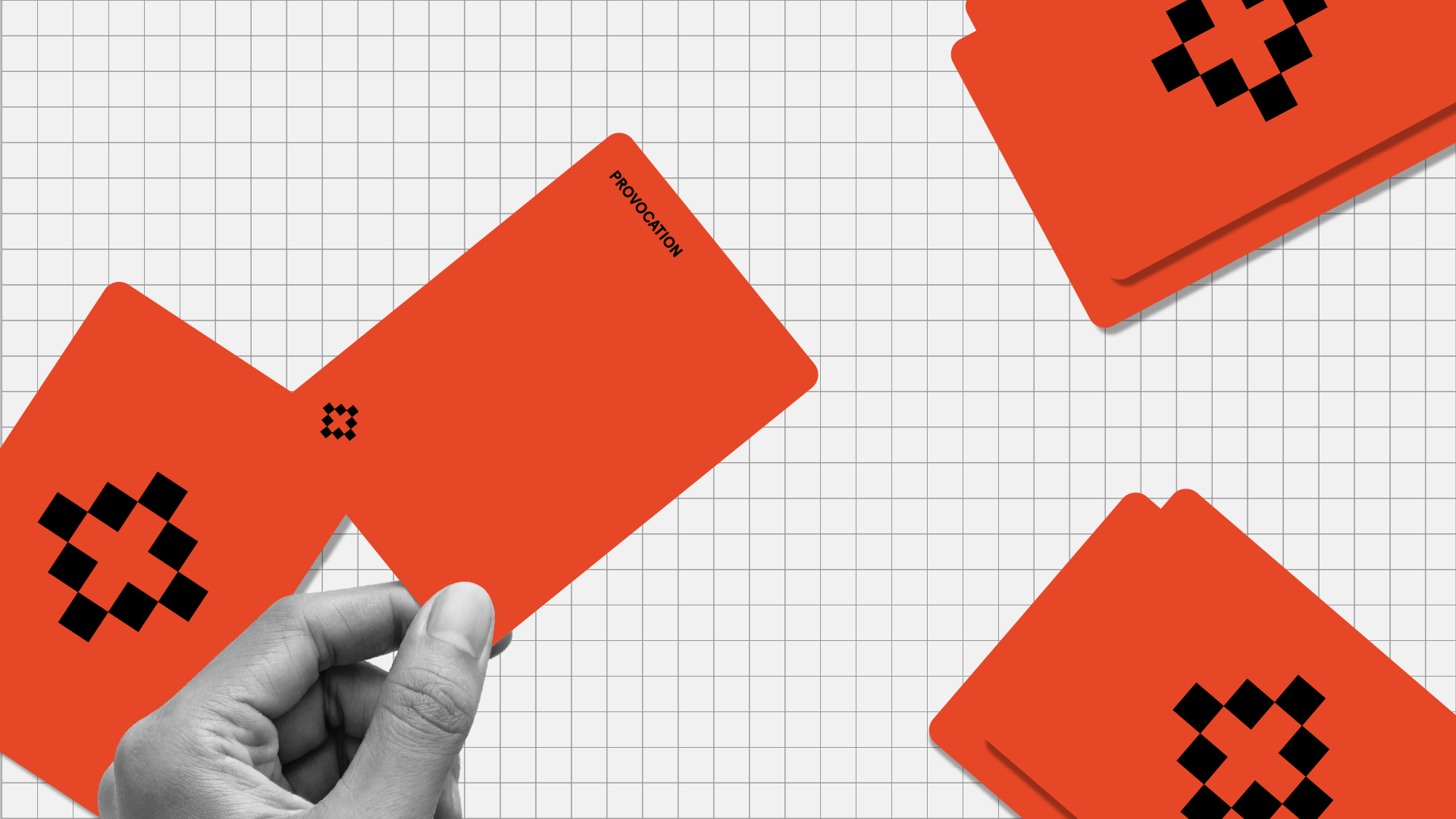 Red cards labelled "PROVOCATION" arranged on white grid background. Cards feature black and red pixel-pattern designs. Hand holding one red card in foreground.