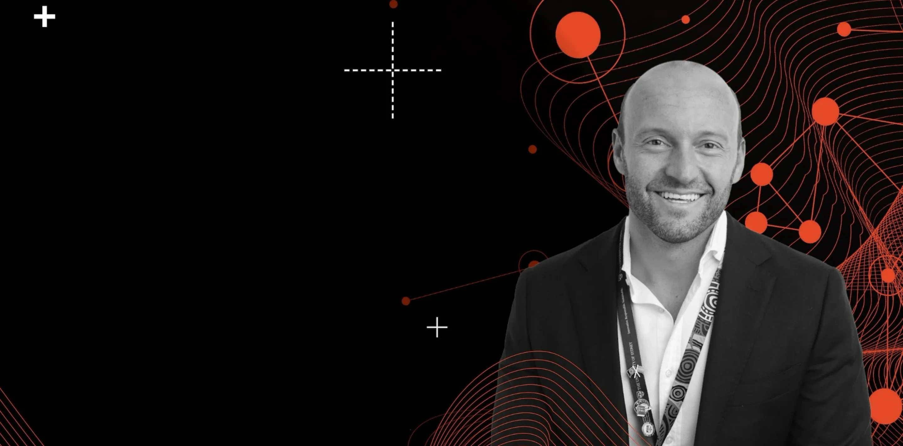 Smiling person in black blazer and white shirt with lanyard, against black background with red abstract network graphics.