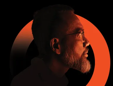 A side profile of a bearded person wearing glasses against a black background with a bold orange circular arc behind them.
