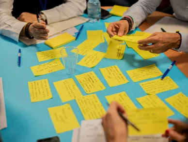 People gathered around a table covered in yellow sticky notes during a workshop or brainstorming session.