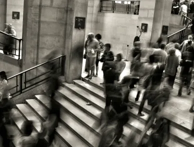 Sepia photo of people walking up and down stairs in an office building.