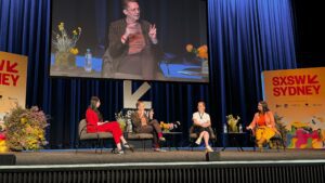 A panel discussion at SXSW Sydney 2023 on the topic of AI fluency and future job impacts, featuring four diverse panelists seated on stage.